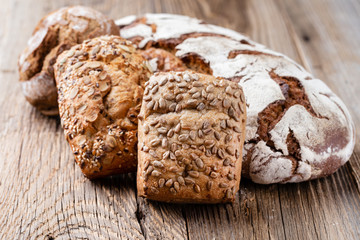 Gold rustic crusty loaves of bread and buns on wooden background. Still life captured from above top view, flat lay.