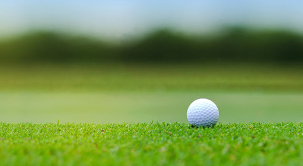 White Golf ball on green course to be shot on blurred beautiful landscape of golf course in bright day time with copy space. Sport, Recreation, Relax in holiday concept 