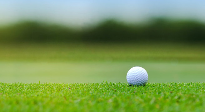 White Golf ball on green course to be shot on blurred beautiful landscape of golf course in bright day time with copy space. Sport, Recreation, Relax in holiday concept	