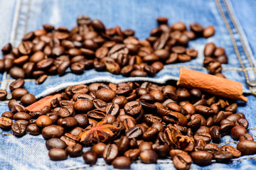 Fresh roasted coffee close up. Beans and spices in jeans pocket. Coffee for inspiration and energy charge. Coffee shop or store. Degree of roasting coffee beans. Texture and background concept