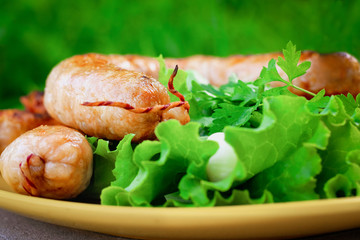 Closeup of barbecue sausages in a yellow plate with lettuce and onion heads