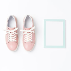 Pink sneakers and empty photo frame. Fashion background