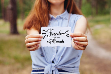 Freedom of speech - young woman holding paper and text outdoors