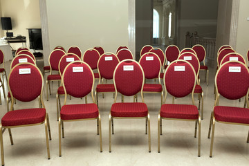 Wedding ceremony in the banquet hall indoors. Rows of chairs for guests at the wedding. A chair in...