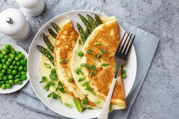 omelette with asparagus and green peas on white plate for breakfast