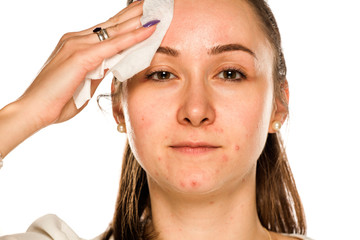 Naklejka premium A woman cleaning her face with cotton pad on white background