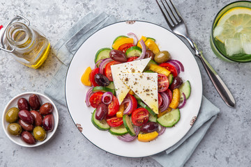 Fresh tomato, cucumber, bel pepper, olives  and feta cheese salad on white plate
