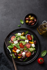 Fresh greek salad with tomato, cucumber, bel pepper , olives and feta cheese on black plate