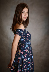 Beautiful brunette woman in sundress on grey background.