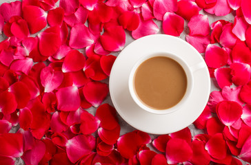 Red rose petals background and a cup of coffee. top view.