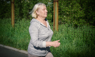 Obraz premium Aged woman jogging in public stadium.