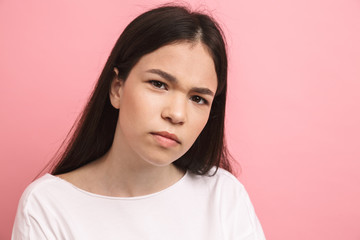 Fototapeta premium Portrait closeup of serious european girl with long dark hair looking and frowning at camera