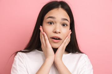 Portrait closeup of excited young girl with long dark hair looking at camera and touching her cheeks