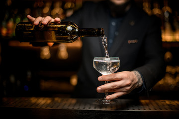 Fototapeta na wymiar Bartender adding sparkling wine in a glass
