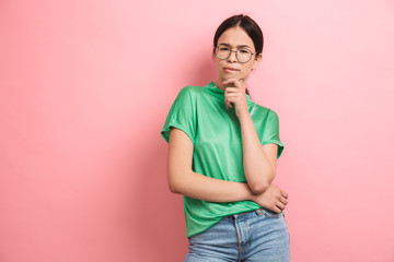 Photo of cute young girl wearing round eyeglasses touching her chin and looking at camera