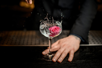 Bartender dropping flower in an alcohol cocktail