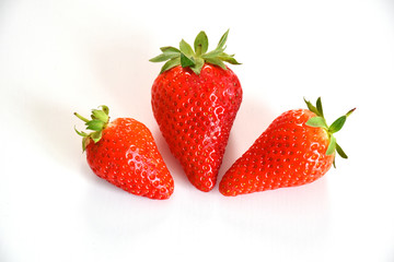 Top view of three red strawberries on white plane 