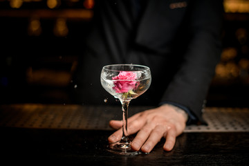 Bartender puts flower in an alcohol cocktail