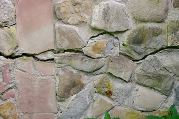 Stone wall of river stones with a large crack in the middle
