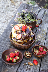 pancakes with chocolate and fresh strawberries in a rustic style on a wooden background