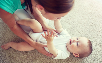family, child and parenthood concept - happy young mother playing with little baby at home