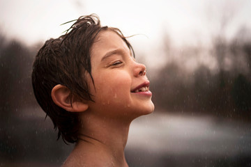 Portrait of a smiling boy standing in the rain