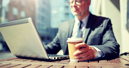 business, hot drinks, technology and people and concept - senior businessman with laptop computer drinking coffee from paper cup outdoors