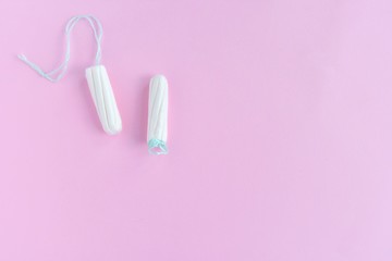 Two cotton tampons for women monthly menstruation with selective focus on blurred pink background. Soft white tampon for female period days on neutral backdrop with empty space for text. Healthcare 