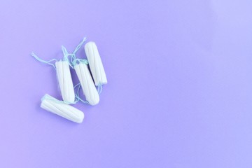 Cotton Hygienic tampons for women period days with selective focus on blurred purple background with empty space for text. Personal protection tampon for menstruated period. Females healthcare 