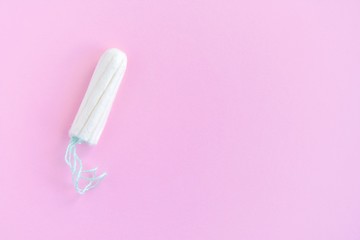 Soft cotton tampon for women period days with selective focus on blurred pink background. Hygiene products for women's monthly menstruation. White protection tampons for female health care. 
