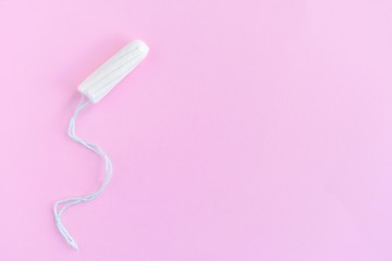 Soft cotton tampon for women period days with selective focus on blurred pink background. Hygiene products for women's monthly menstruation. White protection tampons for female health care. 