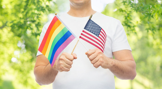 lgbt, same-sex relationships and homosexual concept - close up of man holding gay pride rainbow and american flag over green natural background - Powered by Adobe
