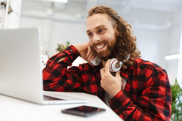 Smiling young bearded man sitting at the cafe indoors