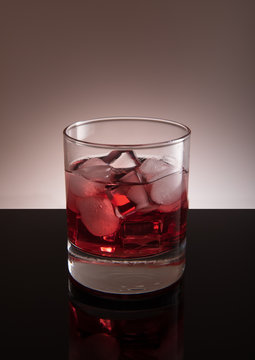 Red cocktail with ice in the transparent glass, isolated