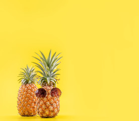 Creative pineapples with sunglasses isolated on yellow background, summer vacation beach idea design pattern, copy space, close up, blank for text