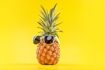Creative pineapples with sunglasses isolated on yellow background, summer vacation beach idea design pattern, copy space, close up, blank for text - obrazy, fototapety, plakaty