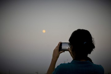 A women capturing the moon on smartphone 