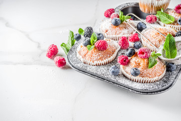 Homemade vanilla muffins or cupcakes with fresh berries on  white marble background