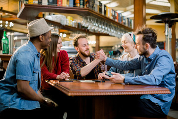 Group of five friends having a meeting in cafe together. Two women and three men at cafe talking laughing and enjoying their time.