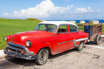 Cuba, rusty and dirty old American car with carriage parked by the sea at Old Havana.