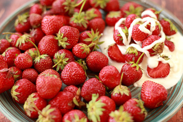 ripe, juicy strawberries with cream in a plate on a wooden table