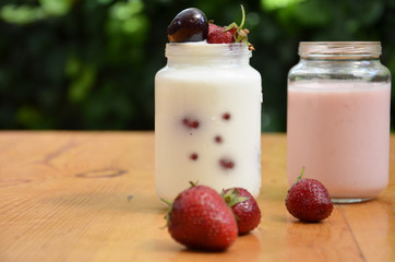 Healthy breakfast - granola, strawberries, cherry, honeysuckle berry, nuts and yogurt in a bowl. Vegetarian concept food. Top view. pudding or cocktail on the background of green foliage
