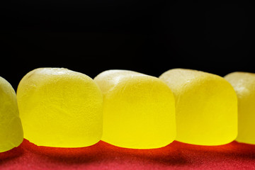 yellow jelly candies close-up lined with a line on a black background
