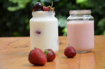 Healthy breakfast - granola, strawberries, cherry, honeysuckle berry, nuts and yogurt in a bowl. Vegetarian concept food. Top view. pudding or cocktail on the background of green foliage