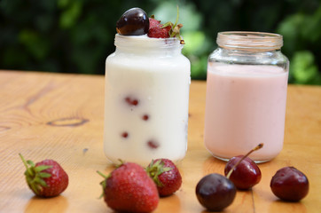 Healthy breakfast - granola, strawberries, cherry, honeysuckle berry, nuts and yogurt in a bowl. Vegetarian concept food. Top view. pudding or cocktail on the background of green foliage