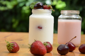 Healthy breakfast - granola, strawberries, cherry, honeysuckle berry, nuts and yogurt in a bowl. Vegetarian concept food. Top view. pudding or cocktail on the background of green foliage