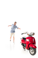 Fototapeta na wymiar handsome stylish young man trying to grab red scooter isolated on white