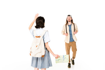 Naklejka premium full length view of young man walking to girl, who waiving her hand and holding map isolated on white