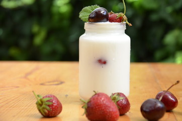 Healthy breakfast - granola, strawberries, cherry, honeysuckle berry, nuts and yogurt in a bowl. Vegetarian concept food. Top view. pudding or cocktail on the background of green foliage