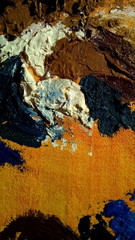 Close-up with oil paint strokes on canvas. Multicolored rough spots on an orange background.